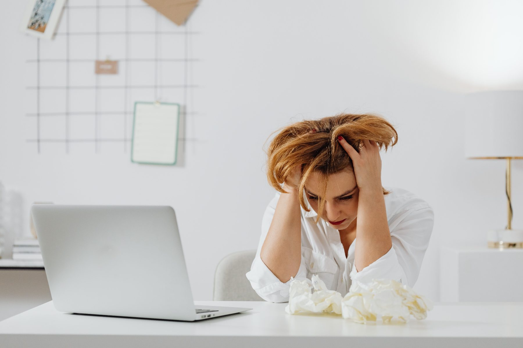 Addetta all'amministrazione davanti al portatile, sommersa dal lavoro manuale